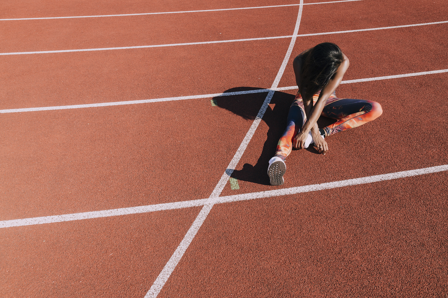 A runner stretches while seated on a track