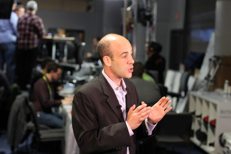 Journalist in a broadcast newsroom [https://www.pexels.com/photo/administration-adult-anchor-anchorman-275496/]