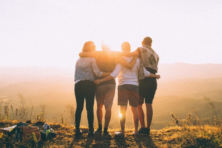 People standing on mountain looking at sunset