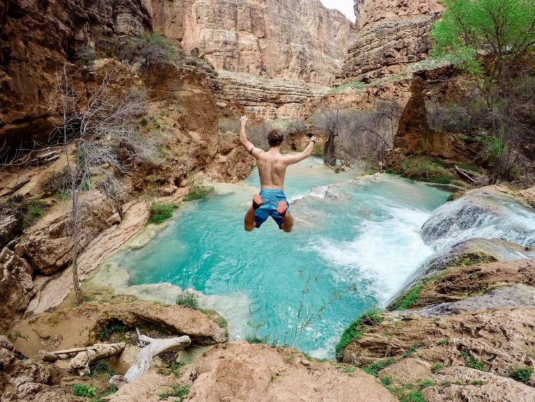 A man jumps from a cliff into the water