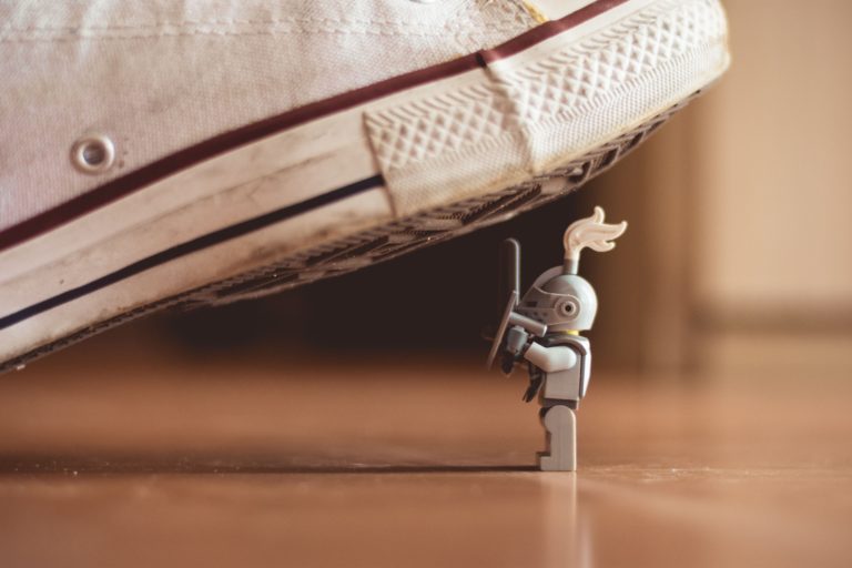 Tiny knight toy with shoe hovering over the top