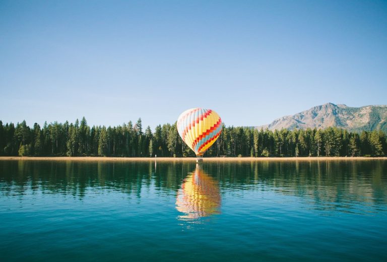 Hot air balloon over a clear blue lake