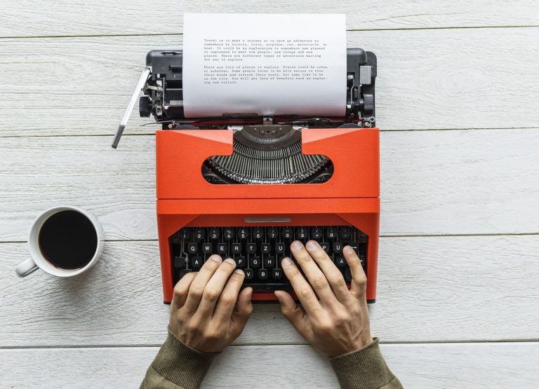 Top down shot a person's hands resting on a typewriter