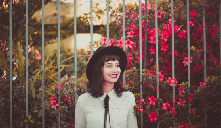 Woman with hat in front of garden