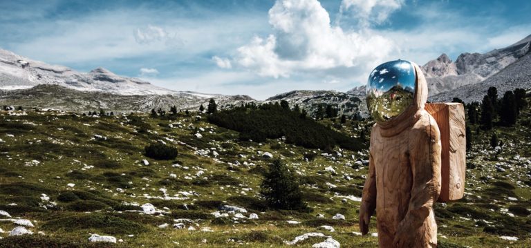 A man hikes through the Swiss Alps in a hazmat suit
