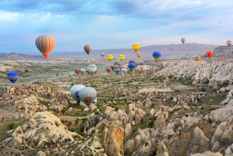Colorful hot air balloons float across a rocky landscape