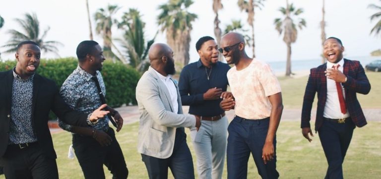 Six friends walking side-by-side and laughing.