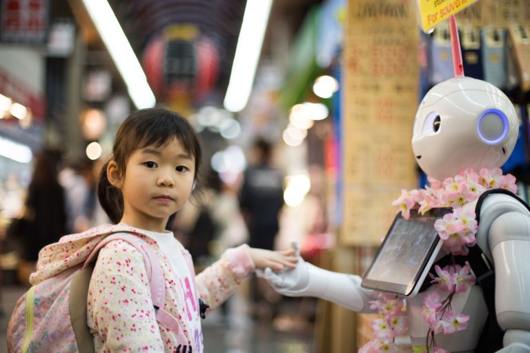 a child interacts with pepper the robot in a market in japan