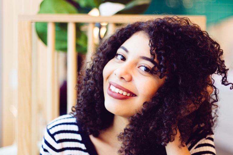 A smiling woman with curly hair and a striped shirt