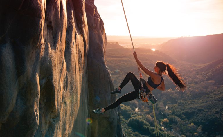 Woman rock climbing outdoors at sunset