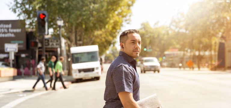 Confident-looking man crosses a sunny street