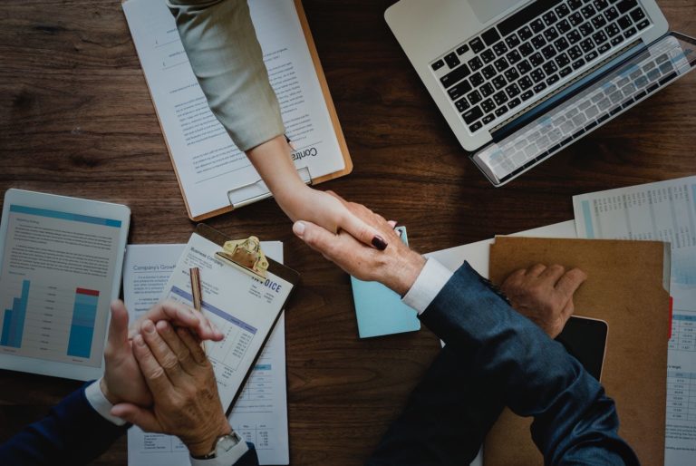 Two professionally dressed people shake hands over a table