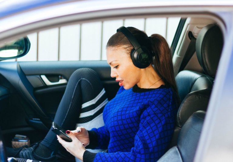 A woman wearing headphones, sitting in her car