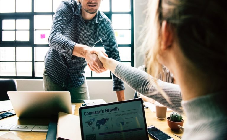 A man and woman shake hands over a table