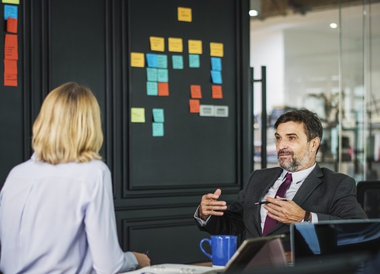 A man and a woman talk in a conference room