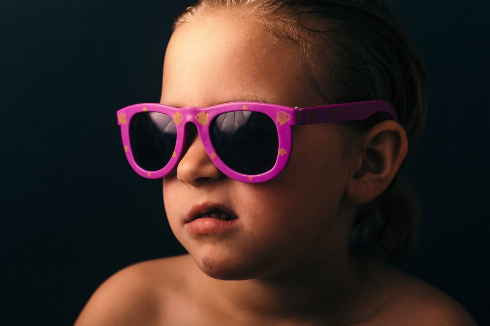 Young child in brightly colored sunglasses, pulling a face