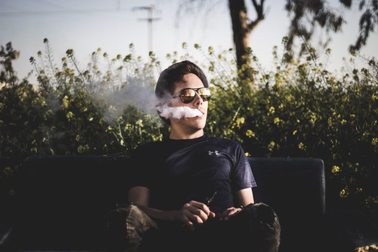 man in sunglasses outdoors smoking marijuana