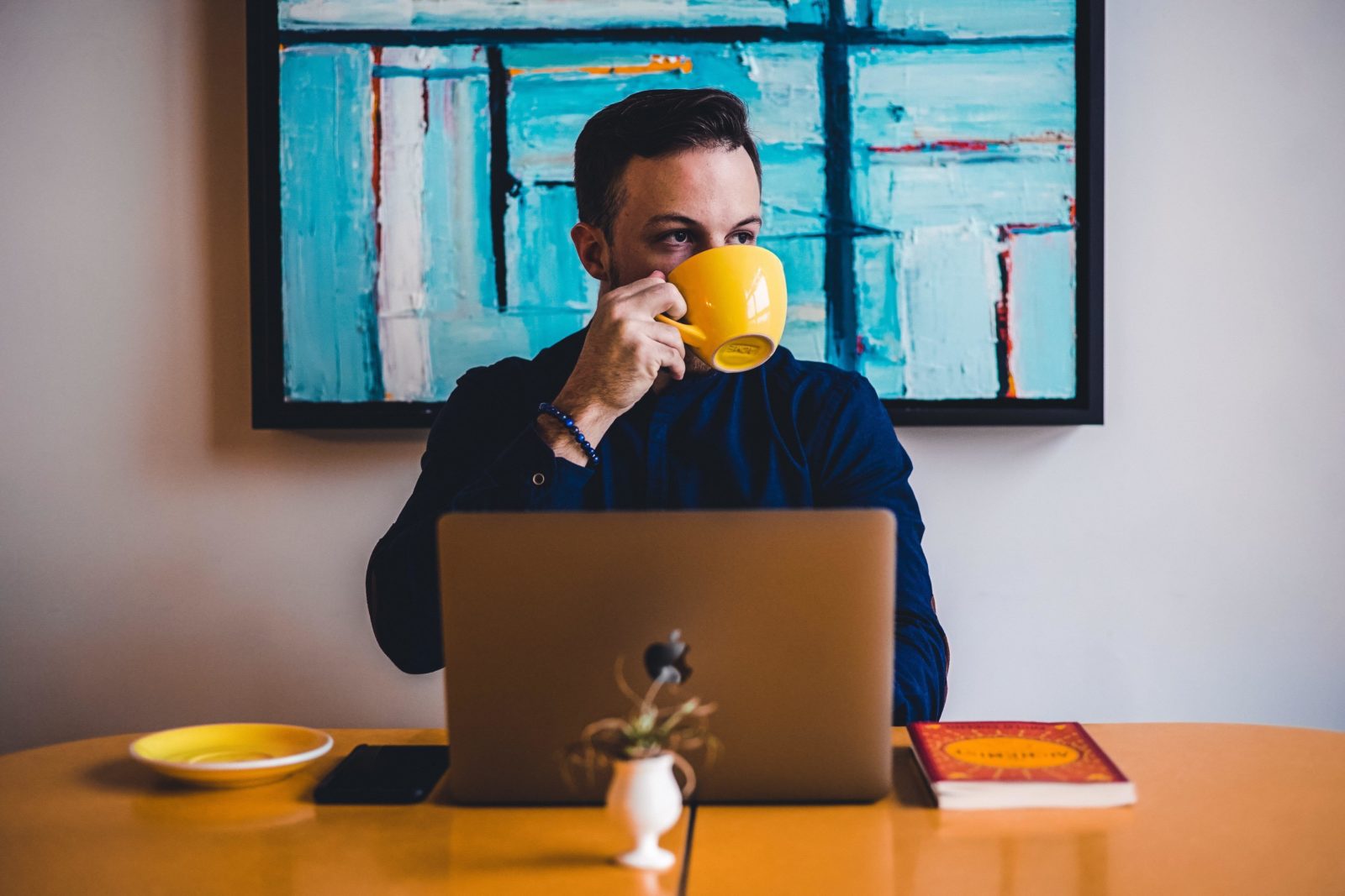 A man sips a cup of coffee at his computer.