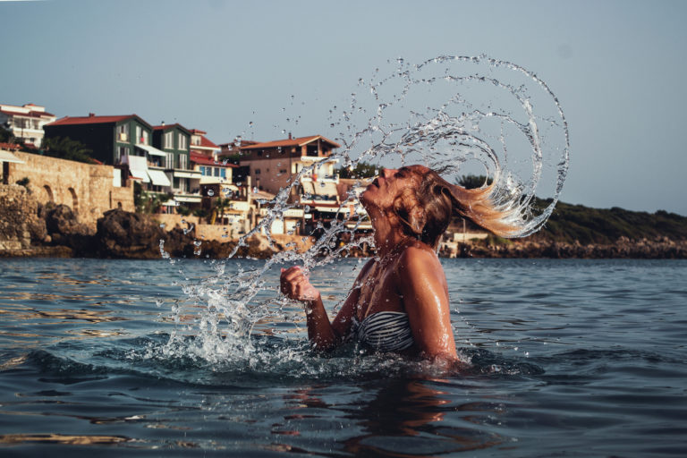 Woman emerging from ocean, flicking hair back