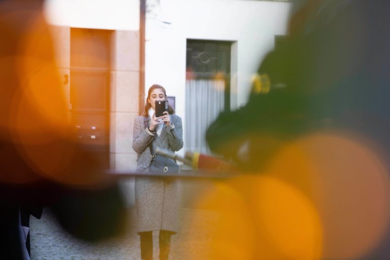 A woman looks at her tablet on a vacant street.