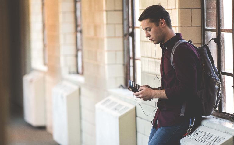A male student checks out a financial app on his smartphone.