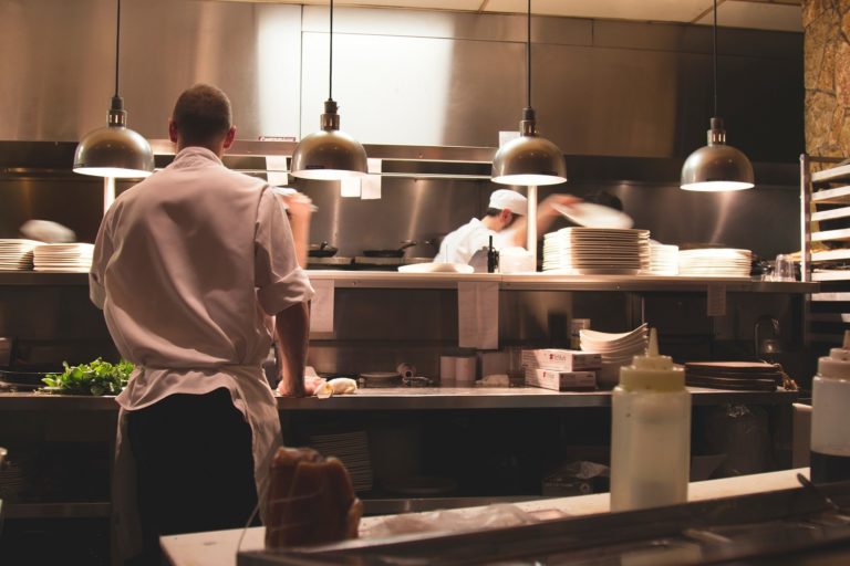 Two men work in an otherwise empty restaurant kitchen.
