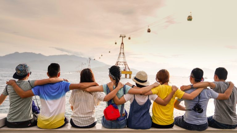 A group of friends with arms around each other, with a mountain in the distance.