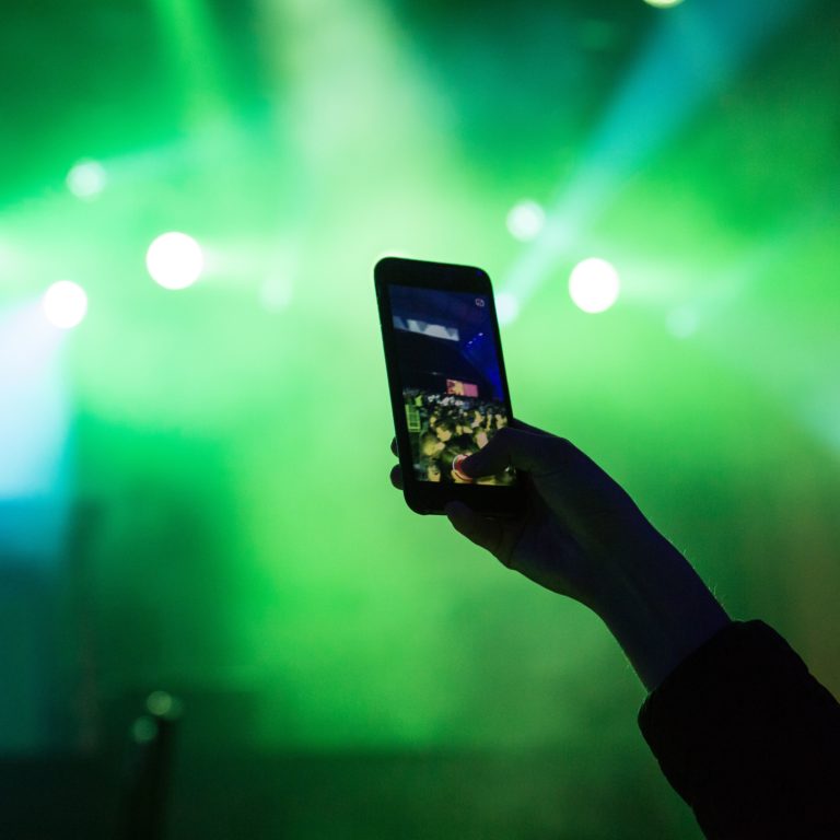 A man films a concert with his smartphone.