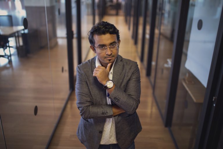 Businessman in a corridor, looking at the camera with a thoughtful pose.