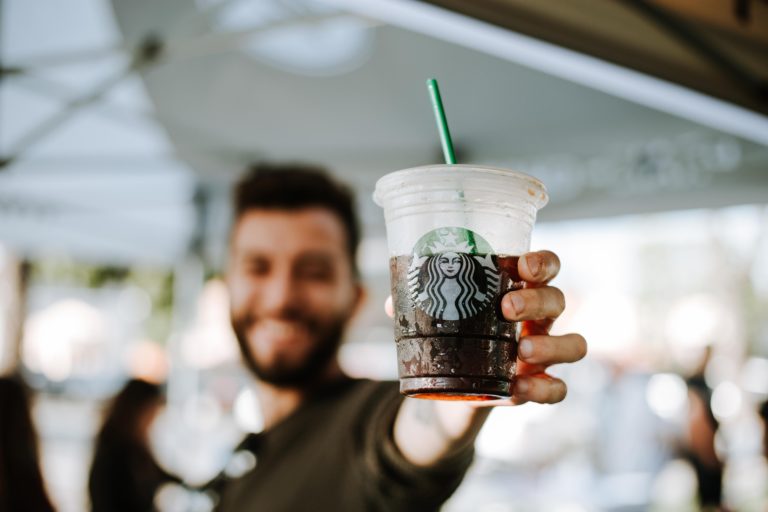 A man holds an iced coffee beverage from Starbucks.