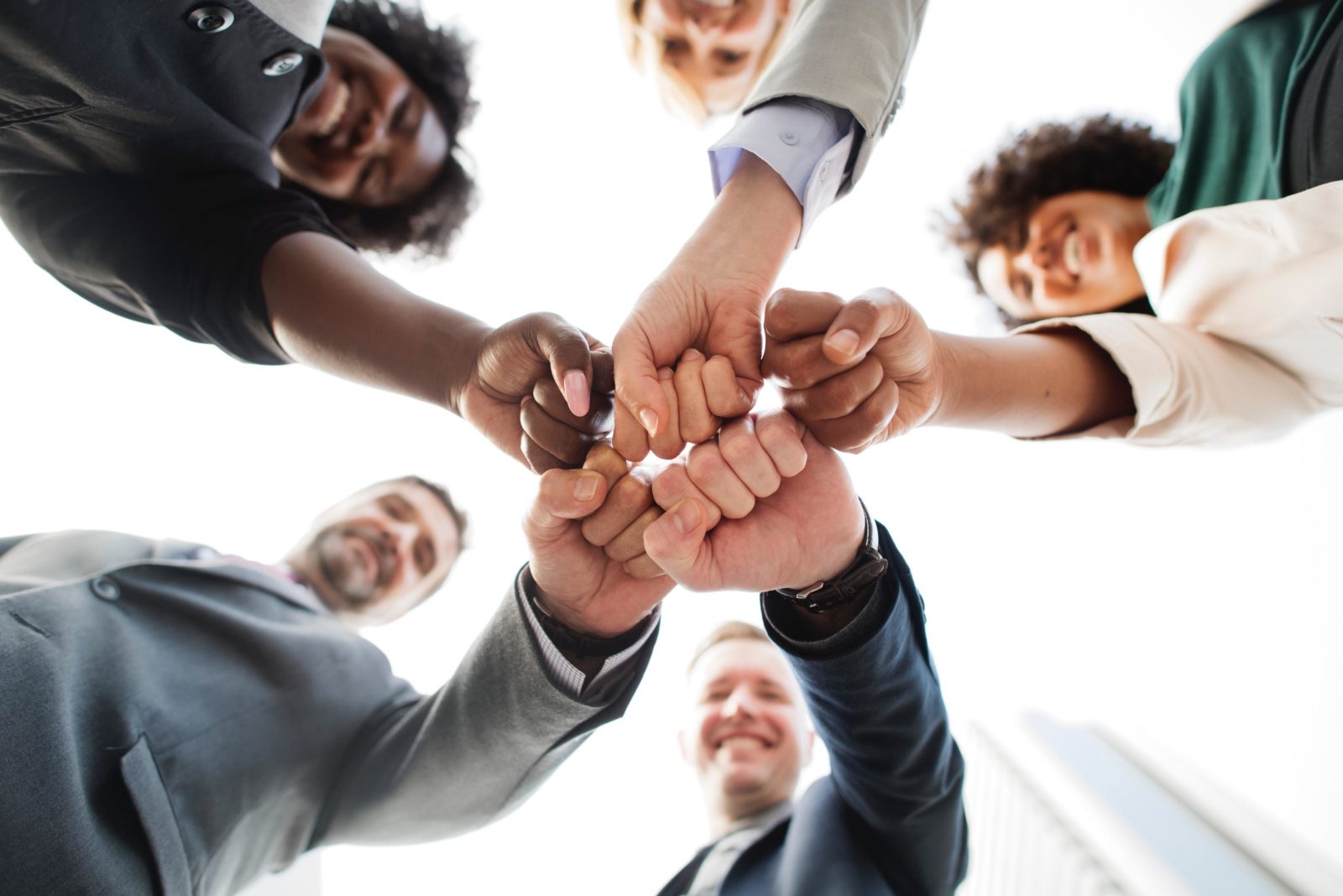 A group of different business leaders gathers in a circle for a fist bump.
