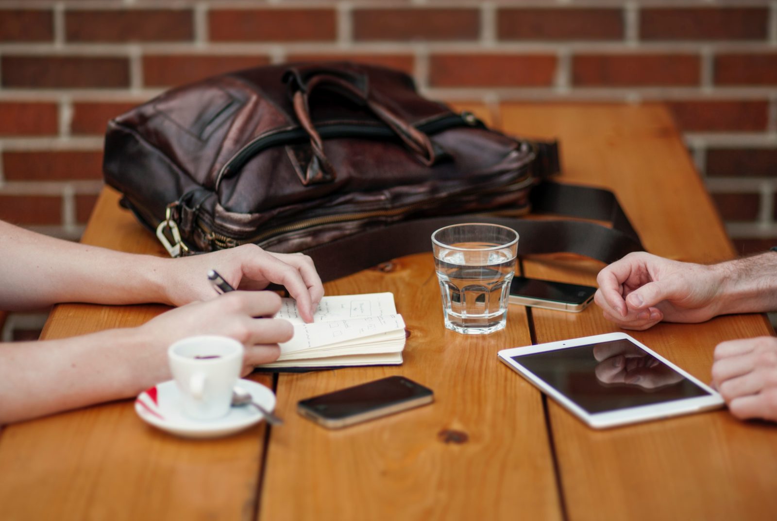 Two people meet at a coffee shop to discuss original research for marketing.