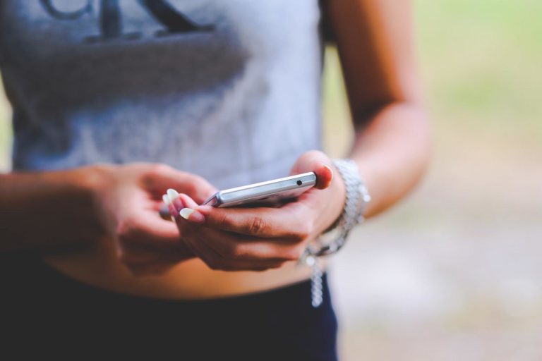 A young woman checks her social media feed on her smartphone.