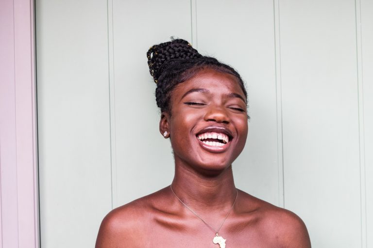 Young woman smiles while wearing a necklace shaped like the continent of Africa.