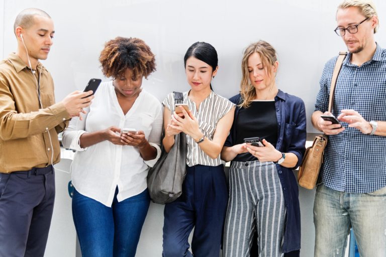 Group of ethnically diverse people browse social media using their smartphones.
