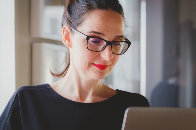 A woman with dark hair and glasses reads a case study on a tablet.