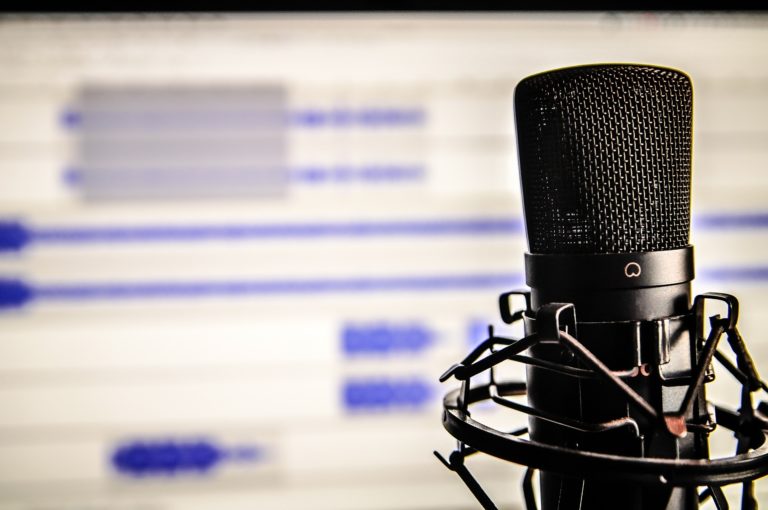 Podcast microphone in front of a digital audio workstation.