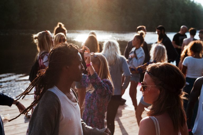 A group of diverse people socializes near a waterfront.