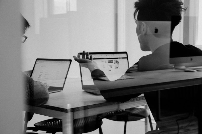 A man in a digital marketing role seen through a glass window on a laptop.
