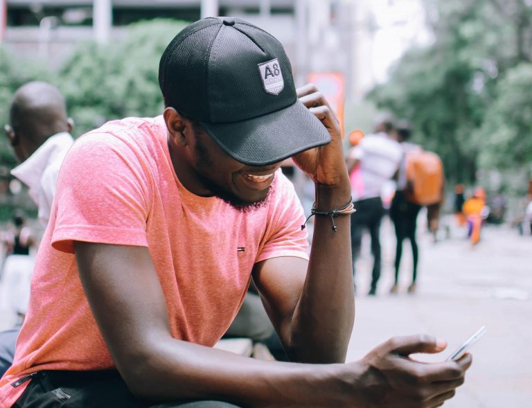 A man wearing a hat browses search engine results on his smartphone.