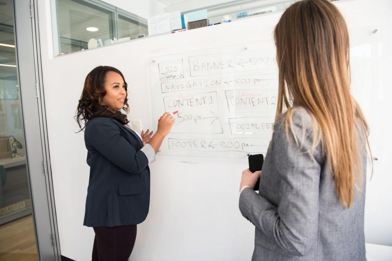 A female content marketing leader points to a content strategy on a whiteboard.