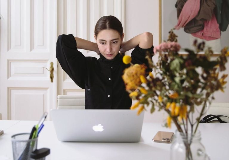 Freelance creative, seated at a wooden desk in a well-lit home office, working on a project.