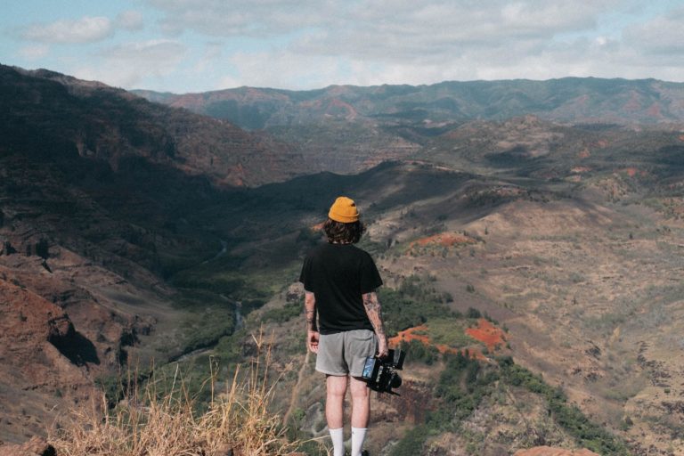 A man standing in front of a canyon holding a camera for video content marketing.