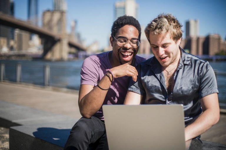 Two men watch a content marketing webinar on a laptop while sitting outside.