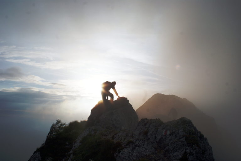 Climber reaching mountain summit.