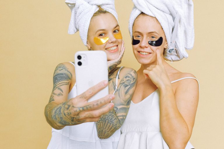 Two women wearing towels and face strips film a video for TikTok.