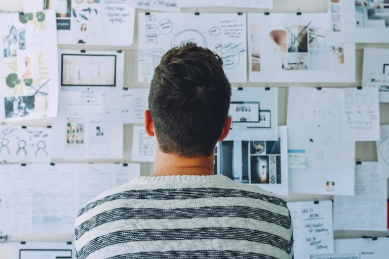 A man stares at a board covered in different content marketing ideas and strategies.