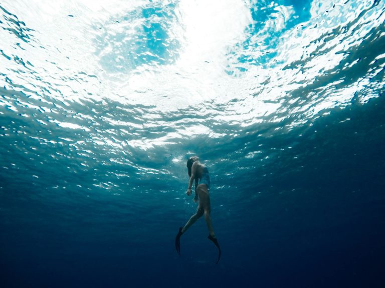 A woman swims underwater while wearing flippers.