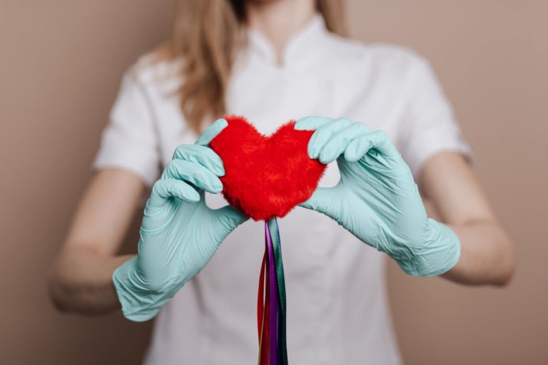 Gloved hands holding red felt heart