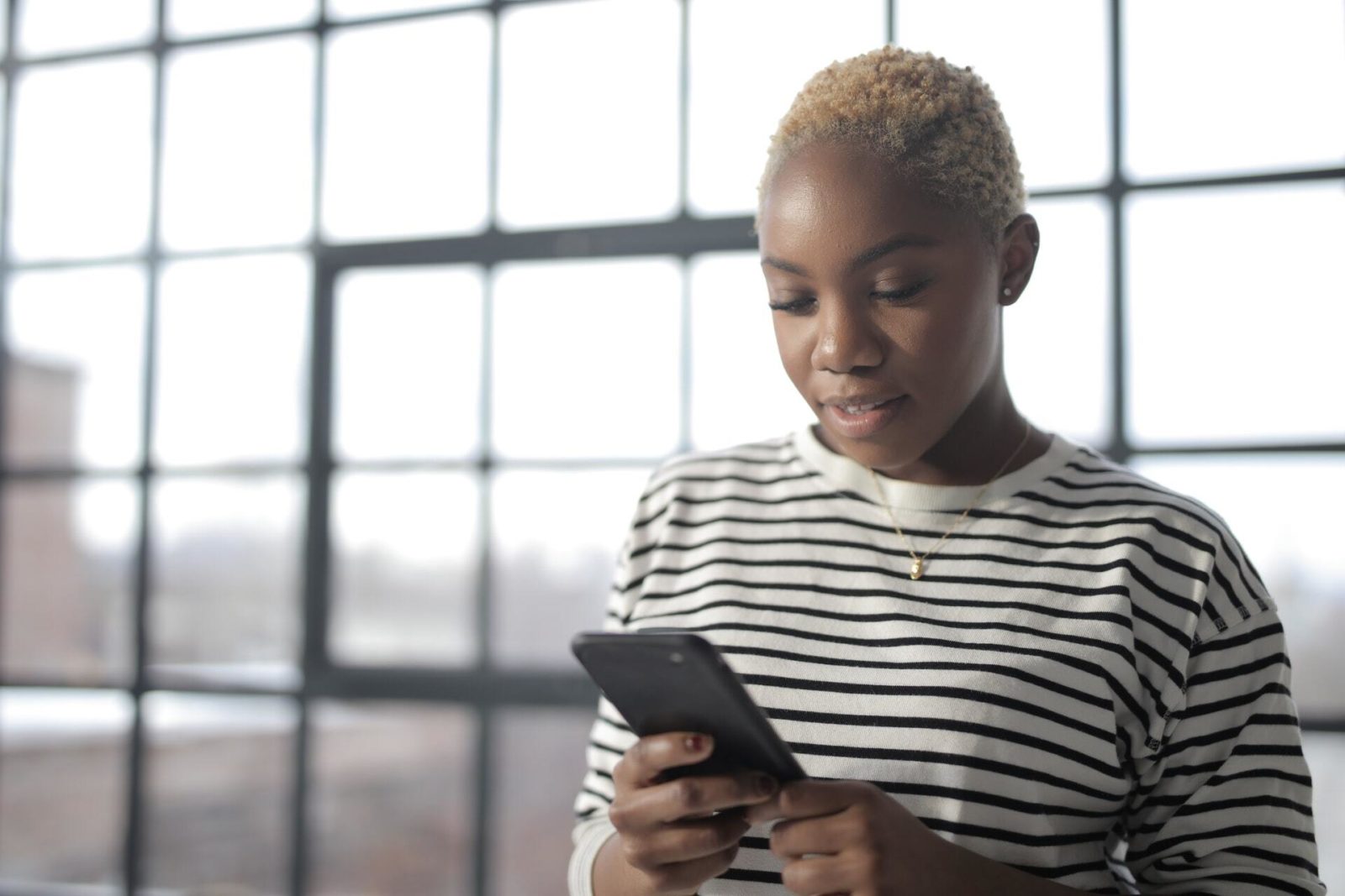 A woman with short hair browses snackable content marketing on her smartphone.
